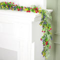 Artificial wildflower garland with pink, yellow, and purple flowers draped over a white mantlepiece.