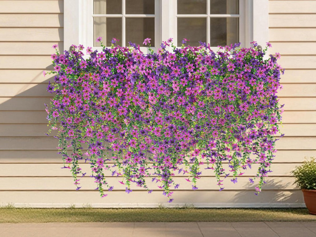 Artificial purple and pink flowers cascading down a wall below a window