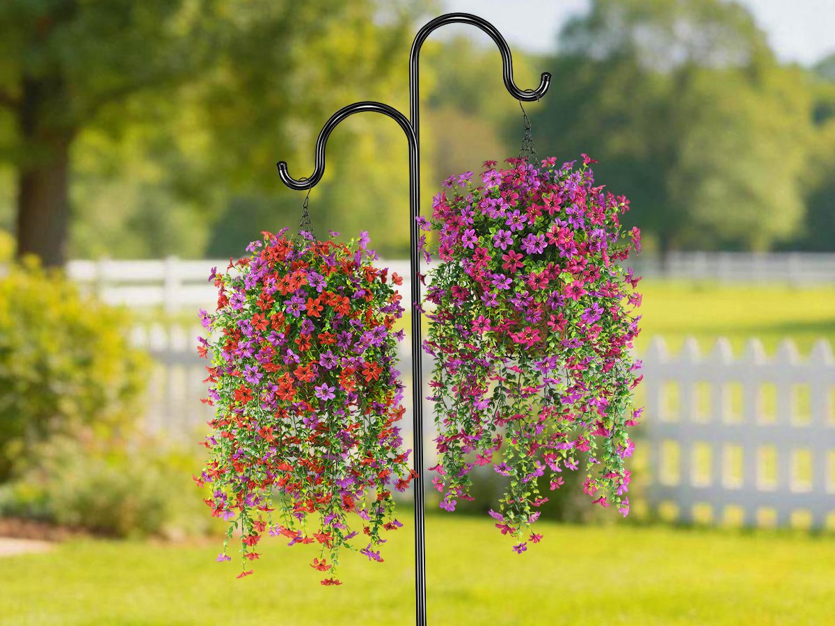Two artificial hanging flower baskets with red and purple blooms, displayed on a shepherd's hook outdoors.