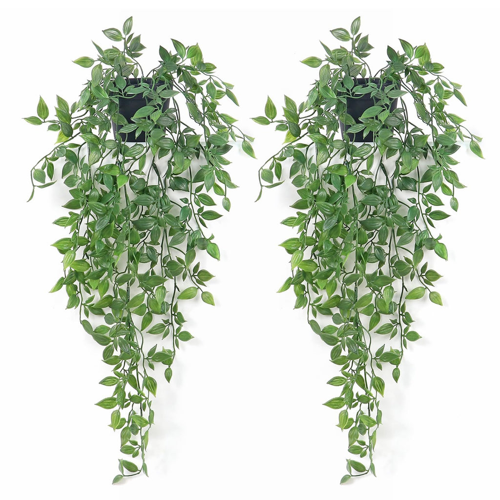 Two artificial green hanging plants with black pots against a white background