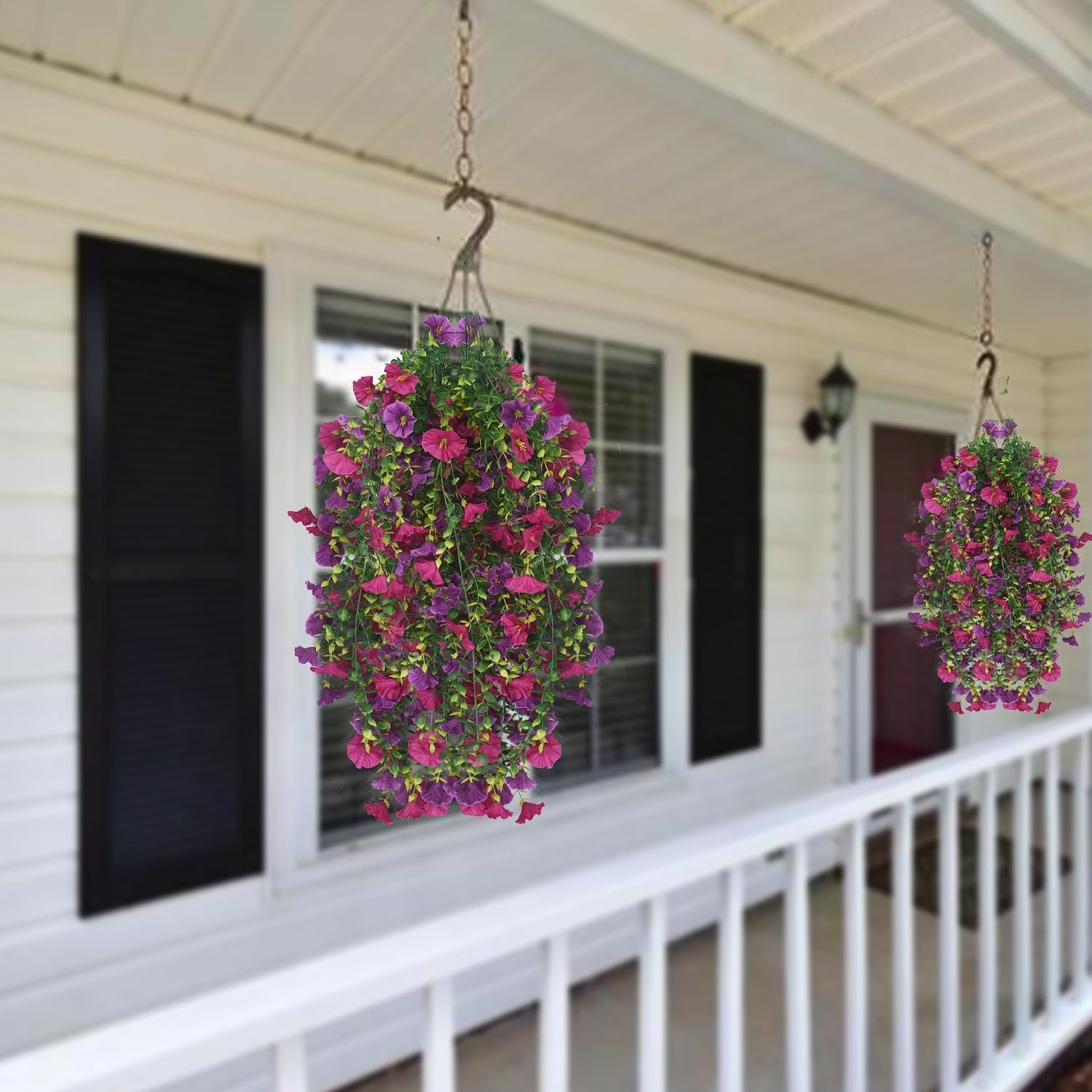Two hanging baskets of artificial purple and fuchsia morning glory flowers on a porch.