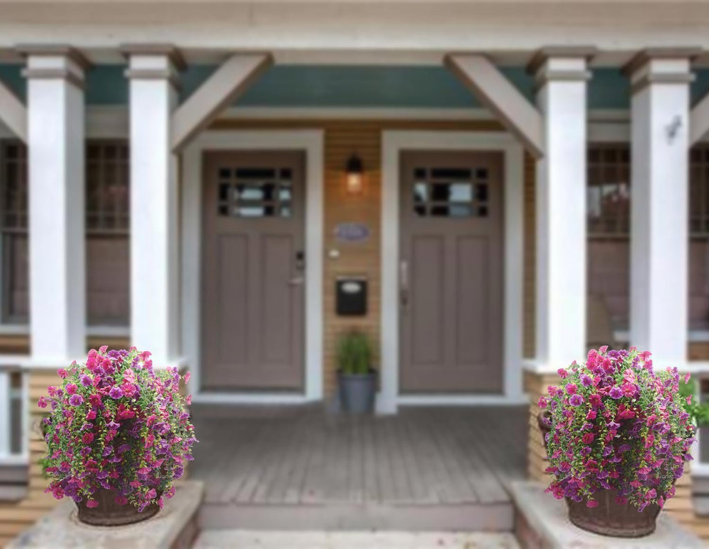 Two hanging baskets of purple and fuchsia artificial morning glory flowers on a porch.