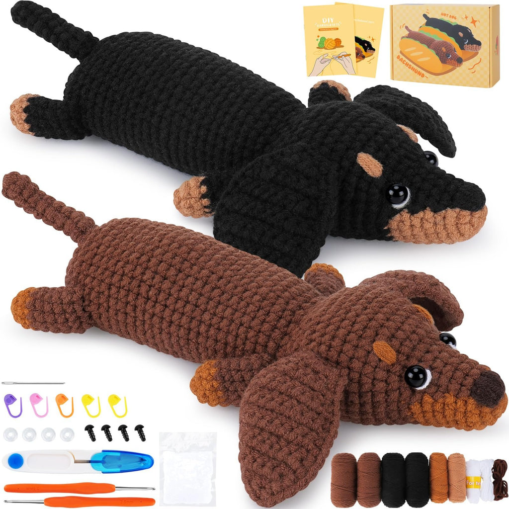 Two crocheted dachshunds, one black and one brown, with crochet kit supplies including yarn, hooks, and stitch markers.