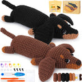 Two crocheted dachshunds, one black and one brown, with crochet kit supplies including yarn, hooks, and stitch markers.