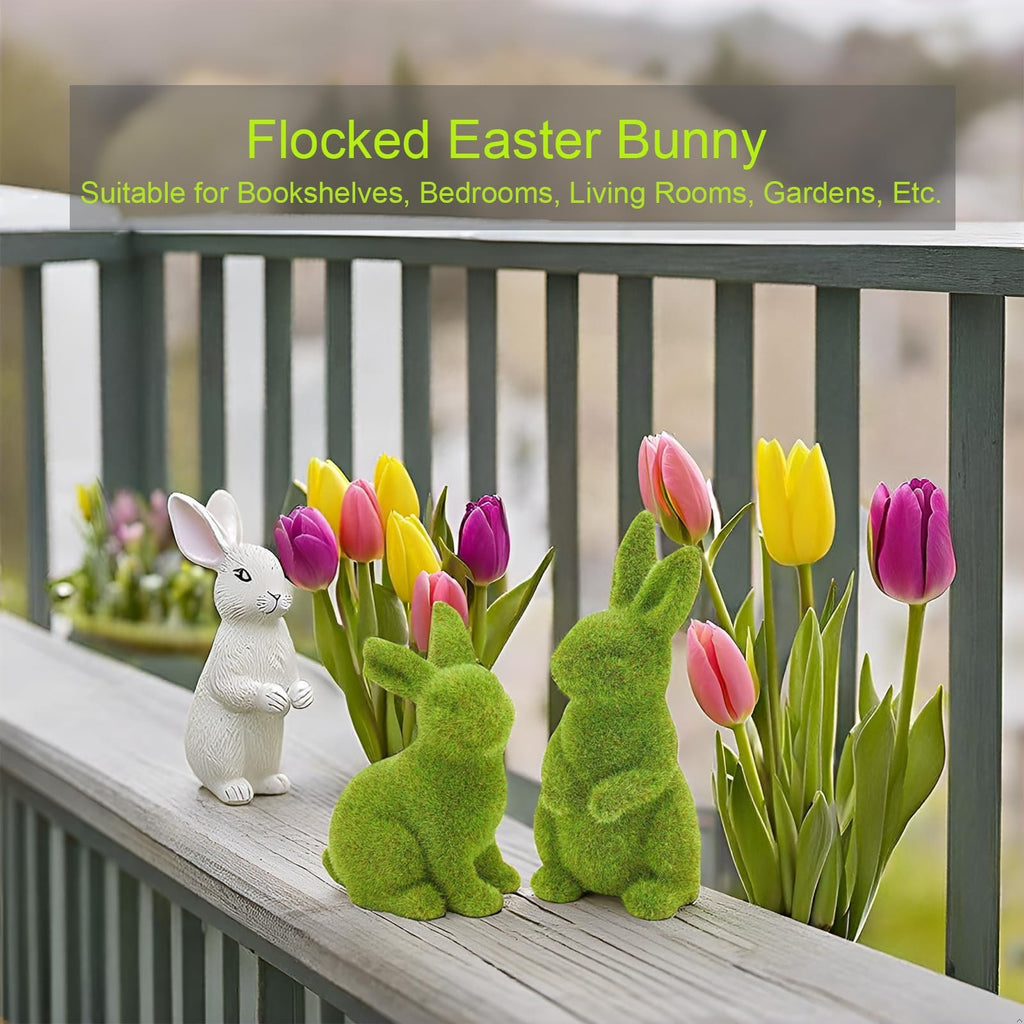 Two flocked green Easter bunny figurines and one white bunny figurine with tulips on a wooden railing.