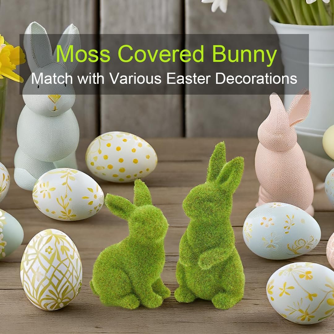 Two green moss bunnies sit among decorative Easter eggs and pastel bunnies on a wooden surface.