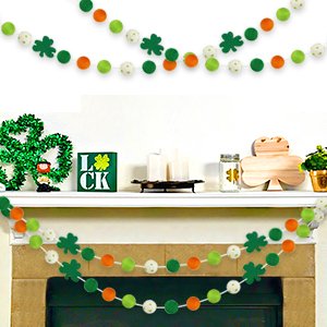 Two St. Patrick's Day felt ball garlands with shamrocks and pom poms displayed on a fireplace mantle and above it.