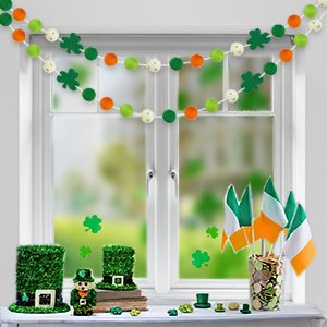 St. Patrick's Day felt ball garlands and shamrock decorations displayed on a windowsill with Irish flags.