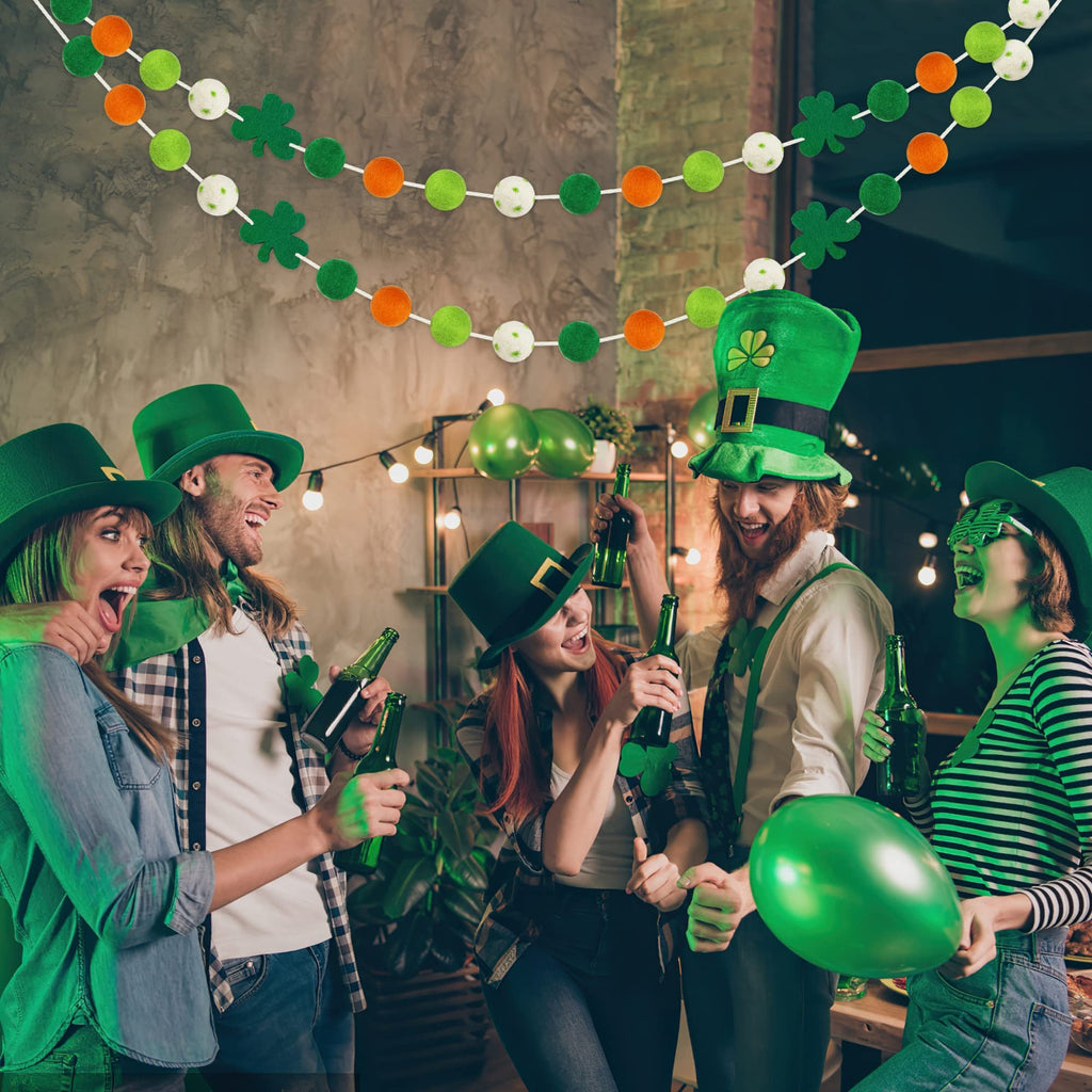 Group of people celebrating St. Patrick's Day with green hats and beer, with felt ball garlands hanging above.