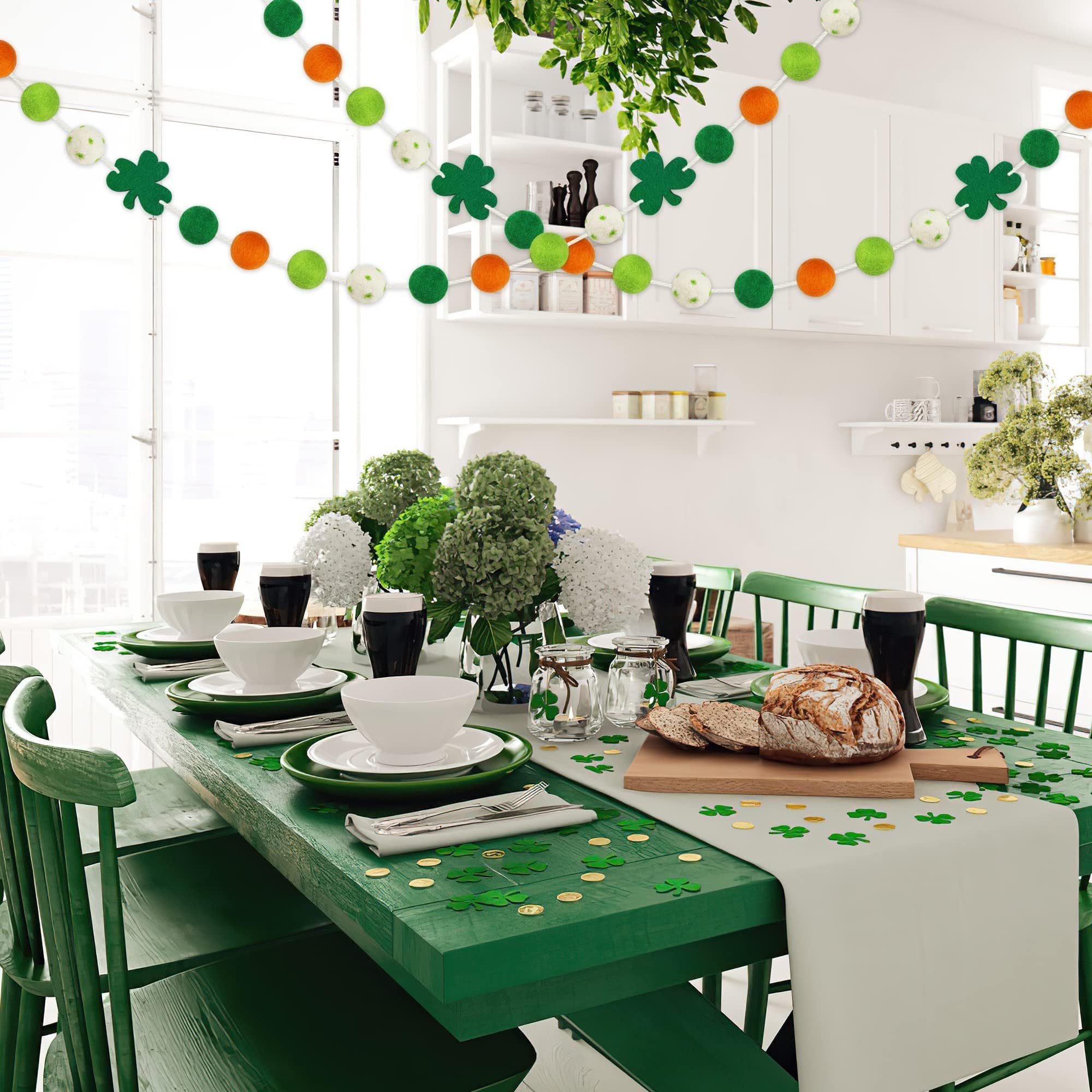 St. Patrick's Day table setting with green felt ball garlands and shamrock decorations hanging above.
