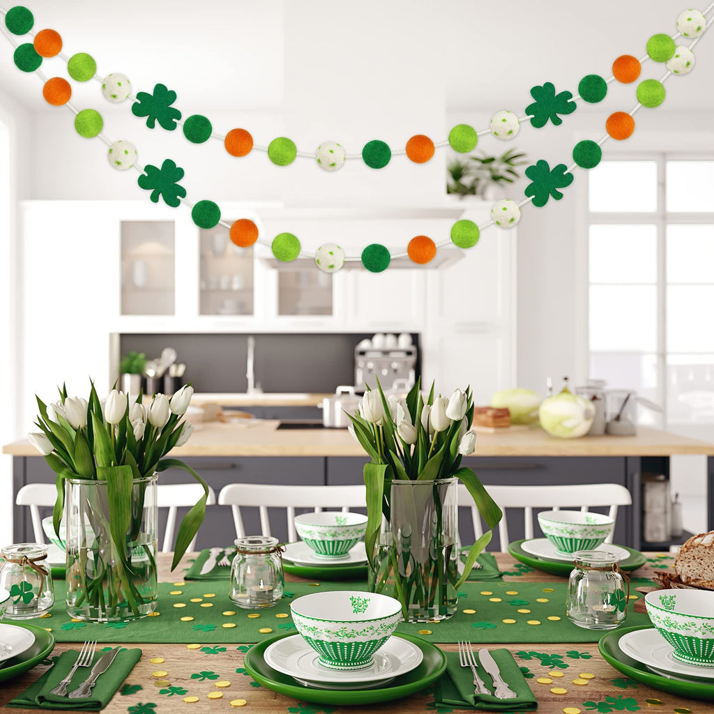 Two St. Patrick's Day felt ball garlands with shamrocks and polka dots draped across a kitchen setting.