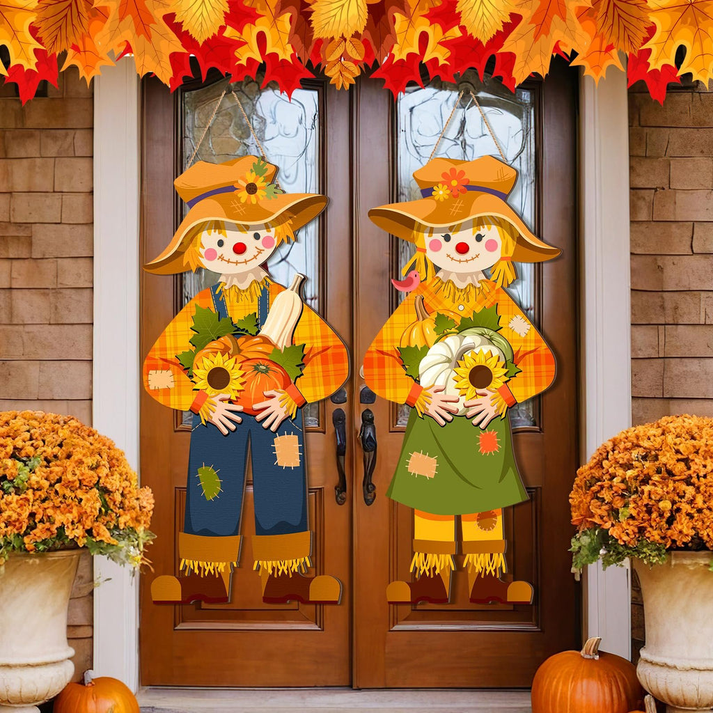Two scarecrow door decorations hanging on a wooden door, adorned with fall leaves garland.