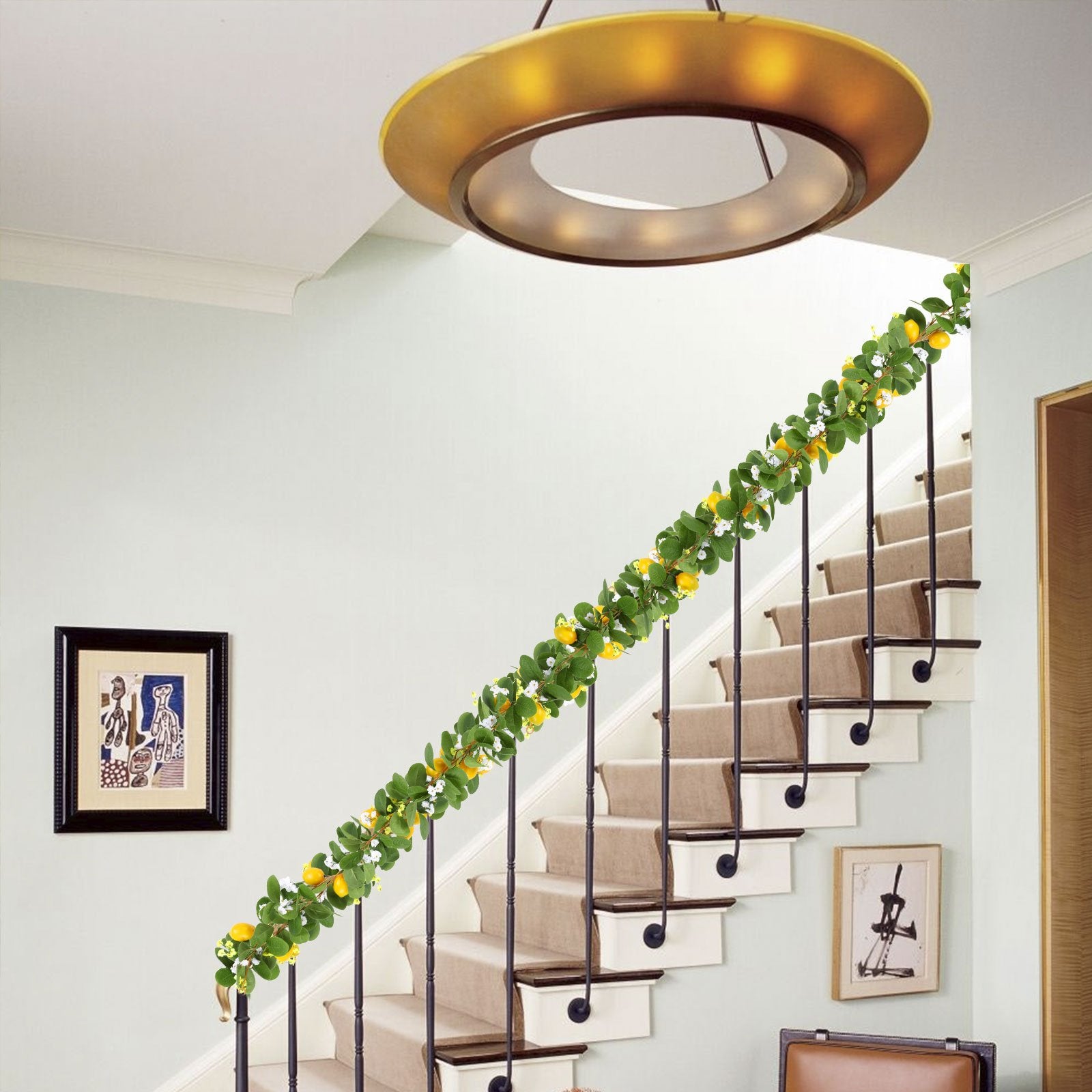 Artificial lemon vine garland with greenery and small white flowers draped along a staircase railing.