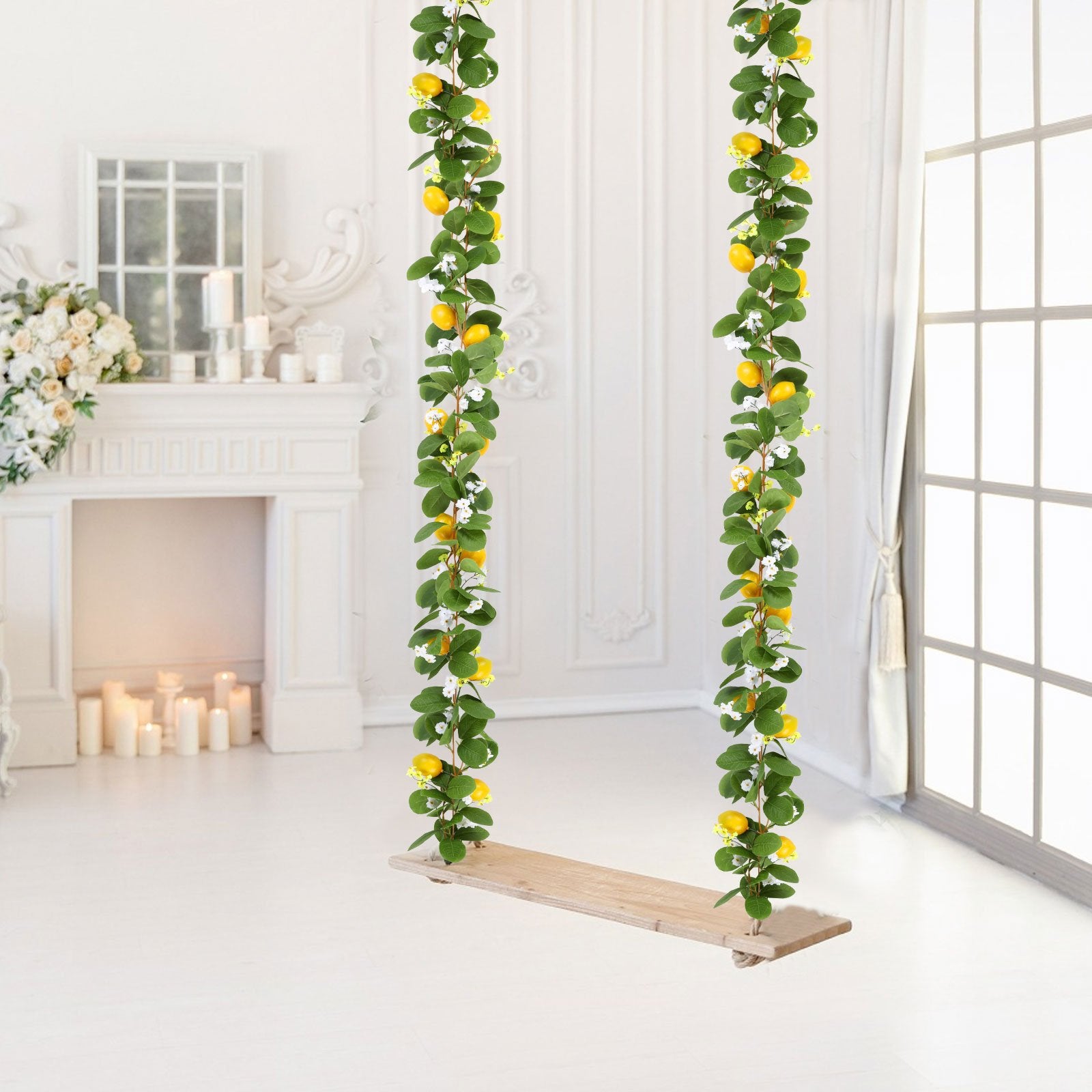 Two artificial lemon vine garlands with greenery and white flowers hanging over a wooden swing seat in a bright room.