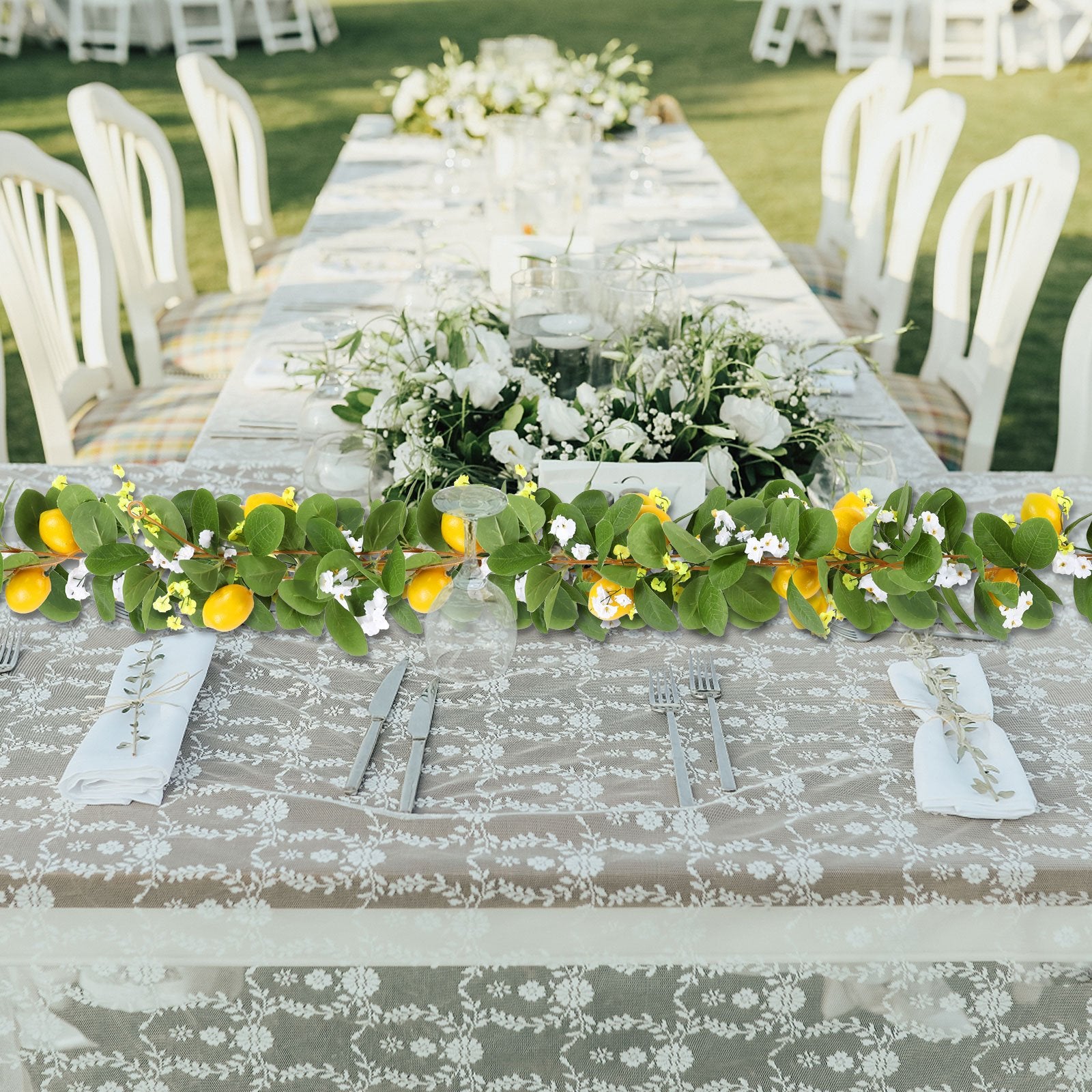 Artificial lemon vine garland with green leaves and yellow lemons draped across a formal table setting.