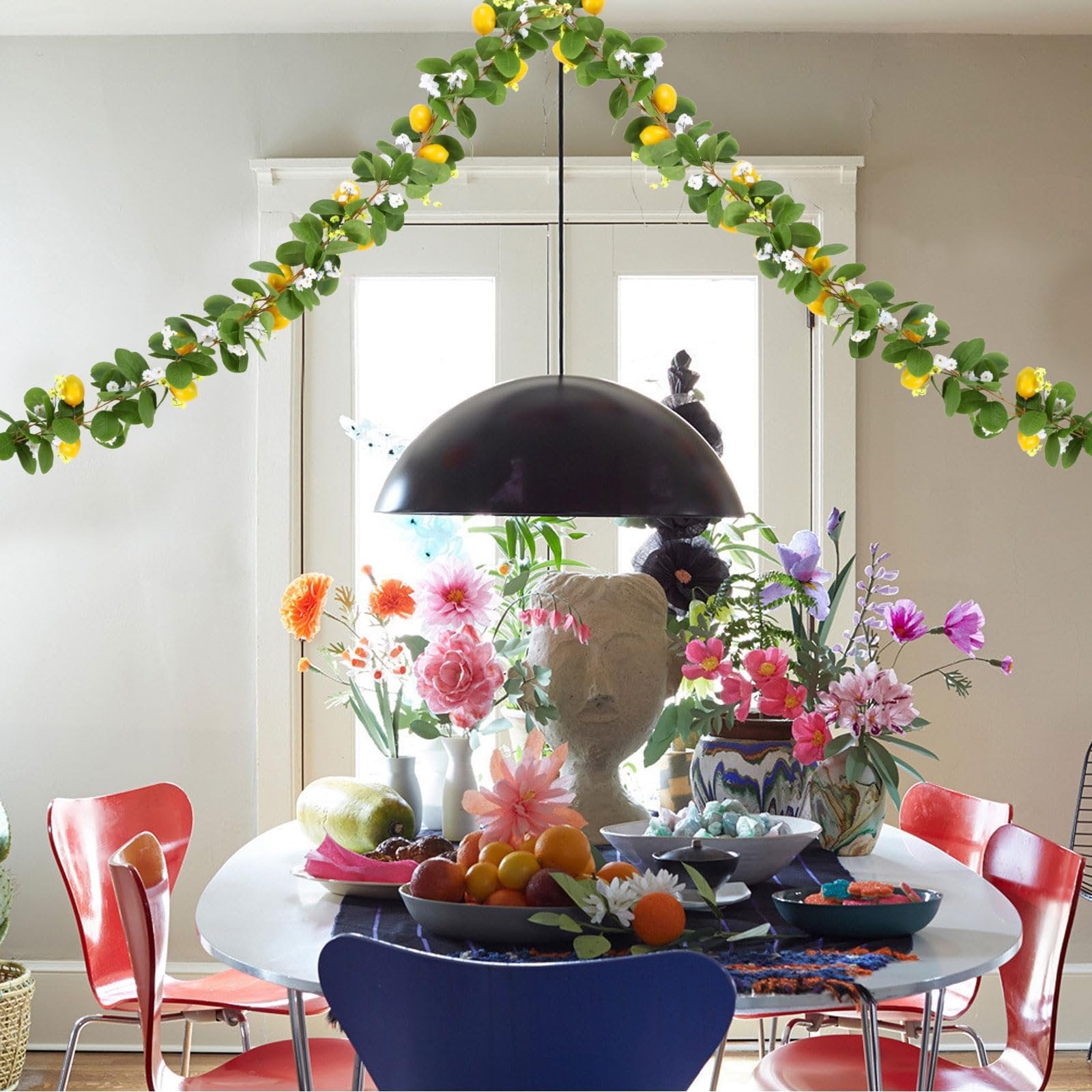 Artificial lemon vine garland draped over a dining table with flowers and fruit