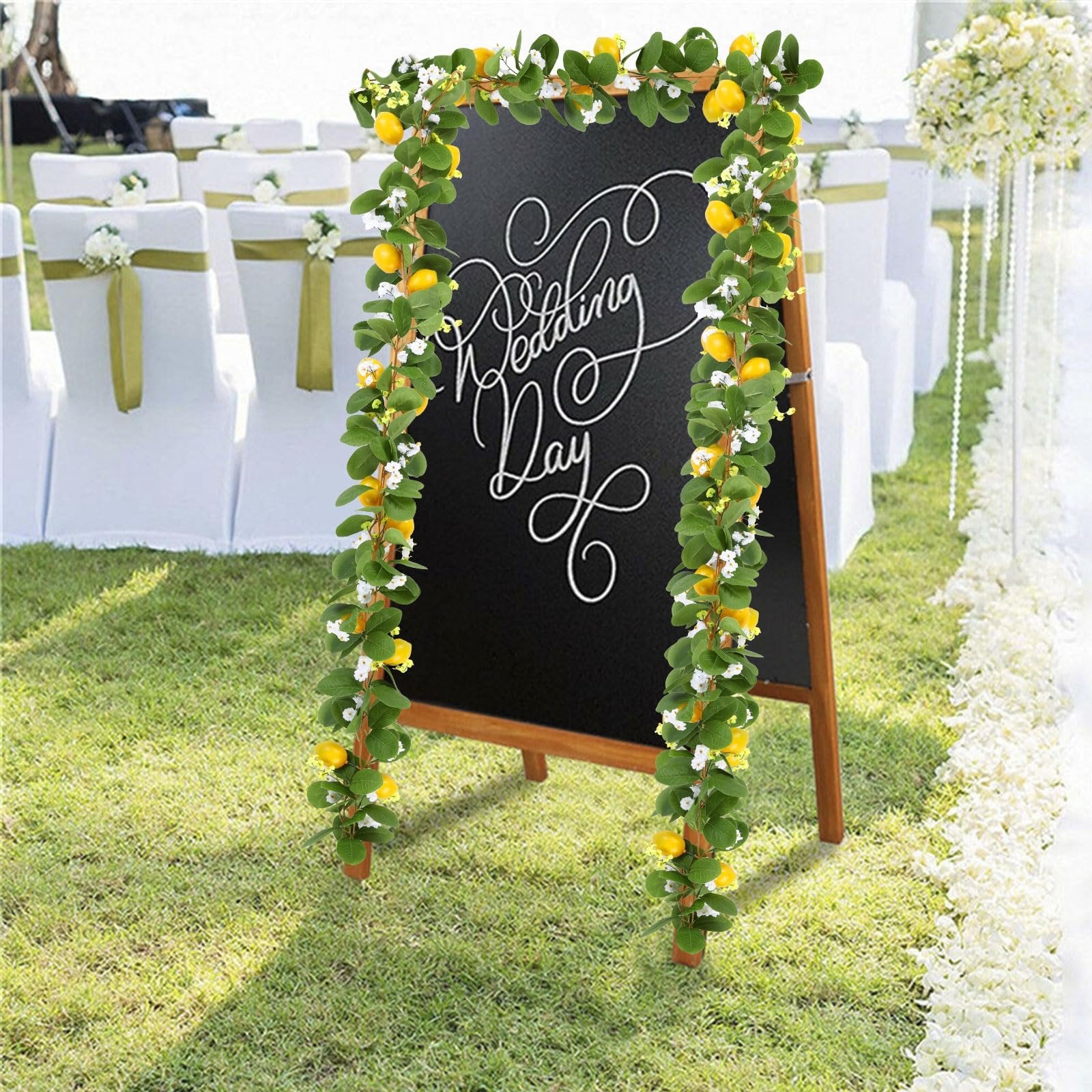 Artificial lemon vine garland with greenery and white flowers draped around a chalkboard that says Wedding Day.