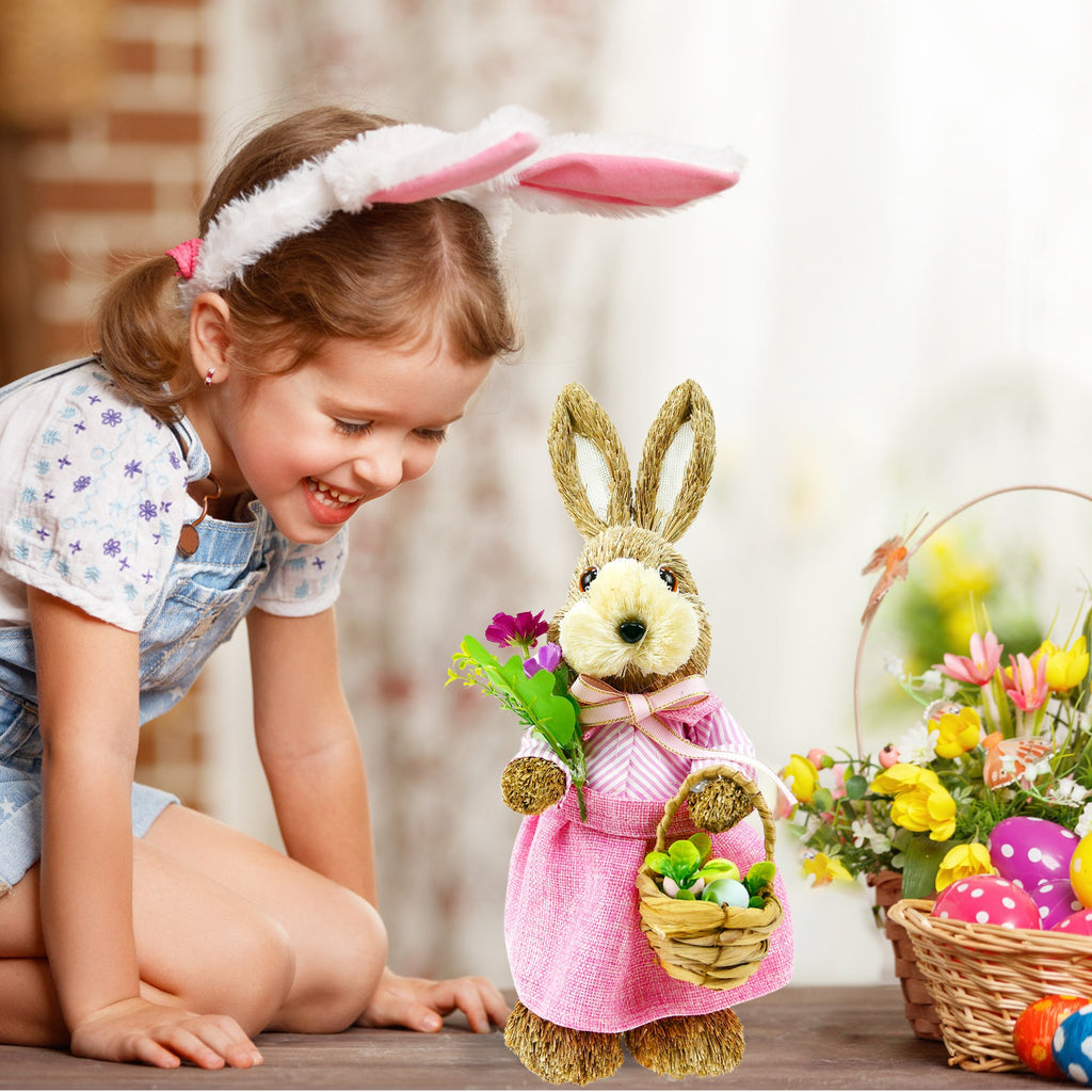Young girl wearing bunny ears looks at a straw bunny figurine holding flowers and a basket with Easter eggs
