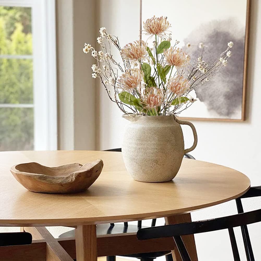 Artificial chrysanthemum bouquet in a rustic vase on a wooden table with a decorative bowl