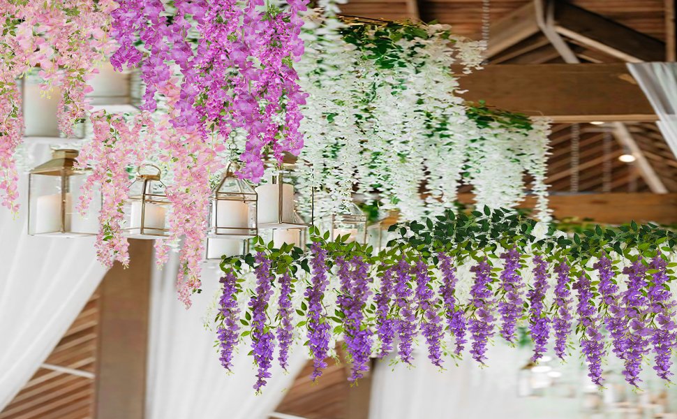 Hanging artificial wisteria flower vines in pink, purple, and white draped from a wooden ceiling with lanterns.