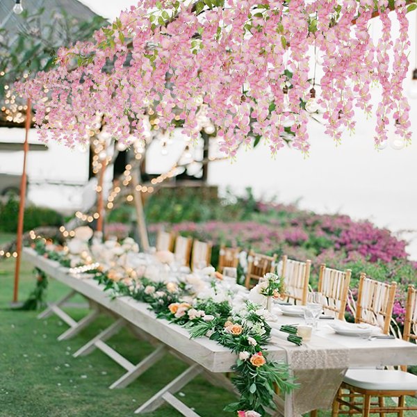 Pink wisteria flower vines draped over a long outdoor wedding reception table setting