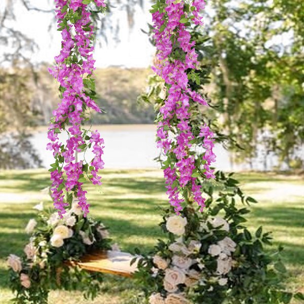 Two hanging artificial wisteria flower vines with pink blossoms and green leaves, draped over a wooden structure with floral arrangements.