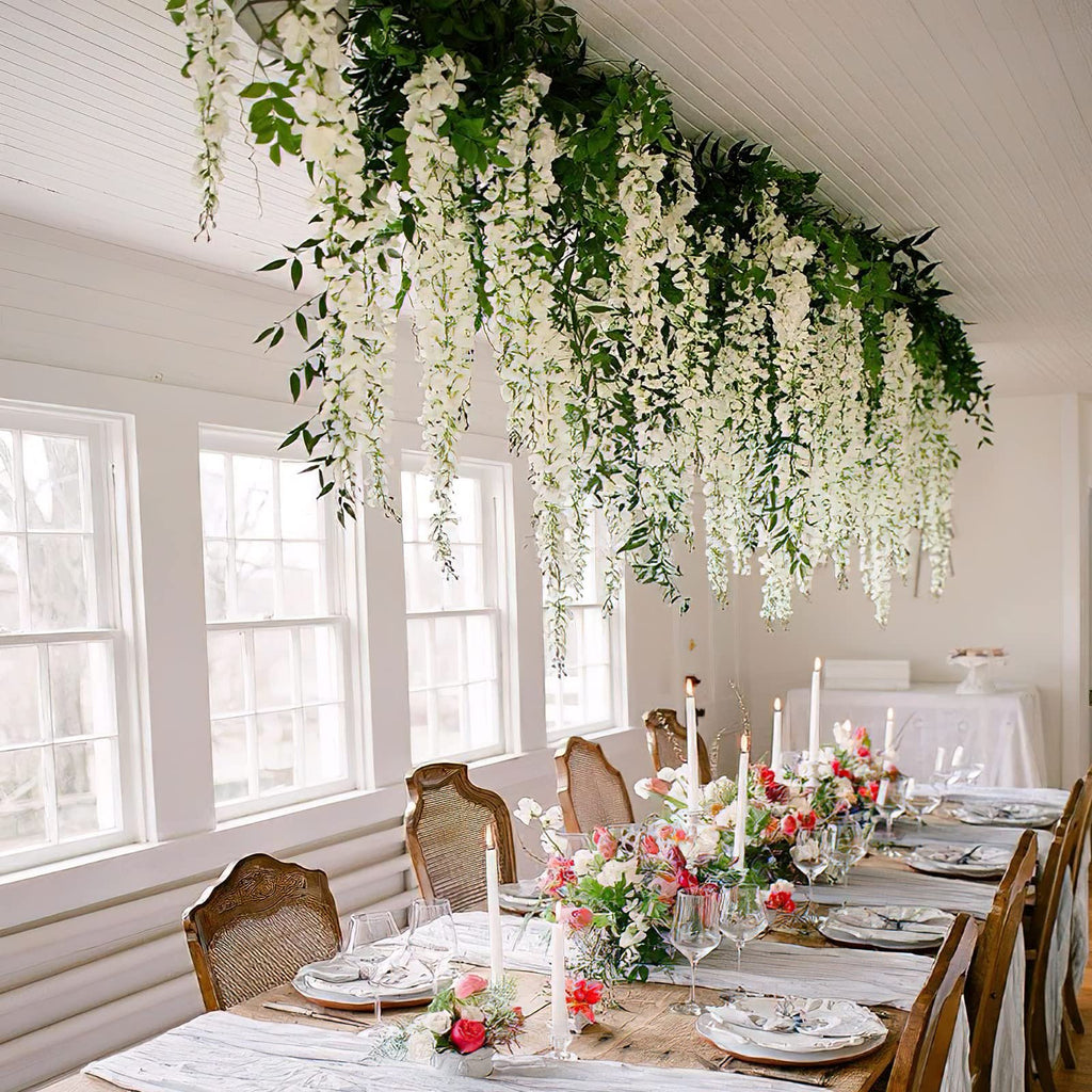 Dining table set with white wisteria floral arrangements hanging overhead and floral centerpieces.
