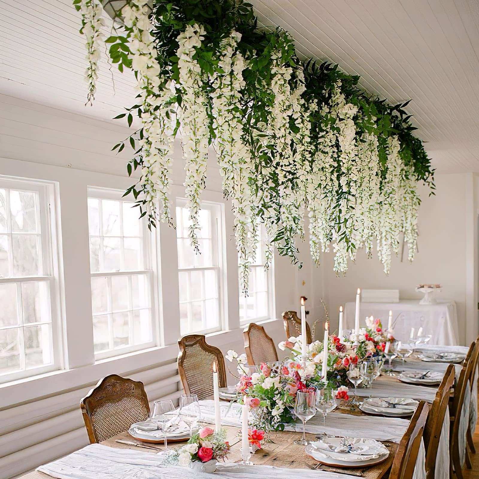 Dining table set with white wisteria floral arrangements hanging overhead and floral centerpieces.
