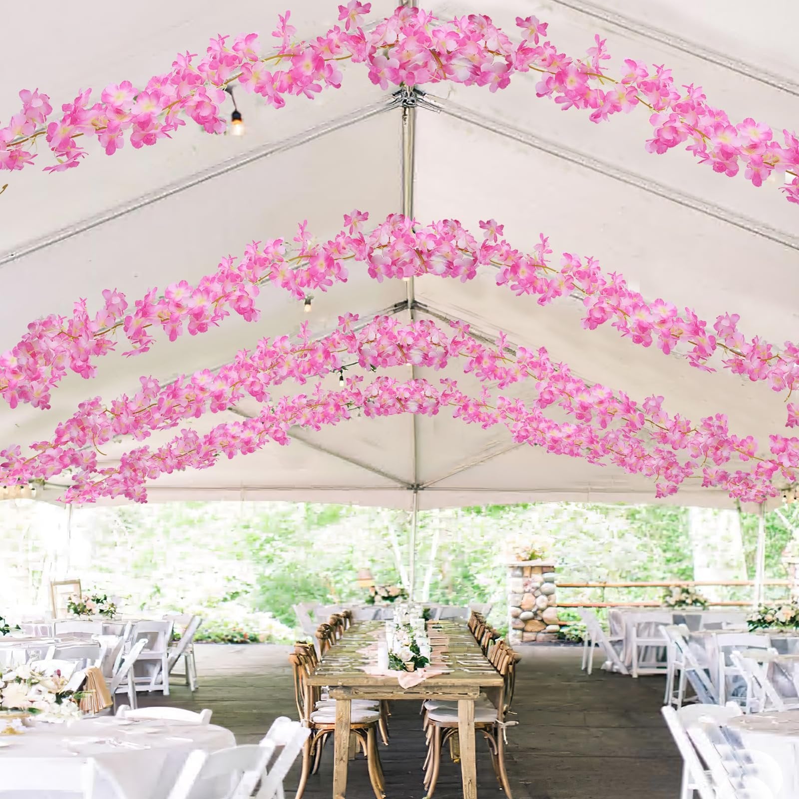 Pink cherry blossom garlands draped inside a tent over tables set for an event