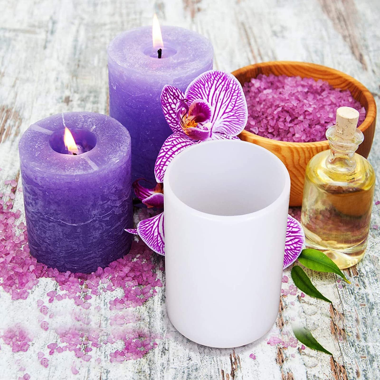 White cylinder resin mold with purple candles, bath salts, and oil on a wooden surface