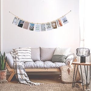 Boho wooden bead garland photo display with clips hanging above a sofa, showcasing various photos and cards.