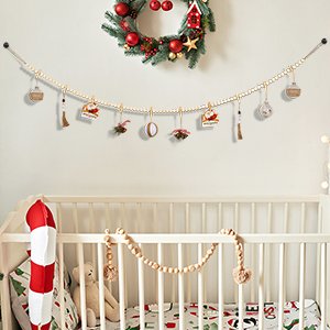 Boho wooden bead garland photo display with clips hanging above a crib, decorated for Christmas