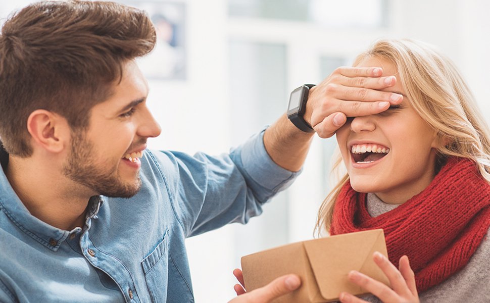 Man surprising woman with a gift box, covering her eyes