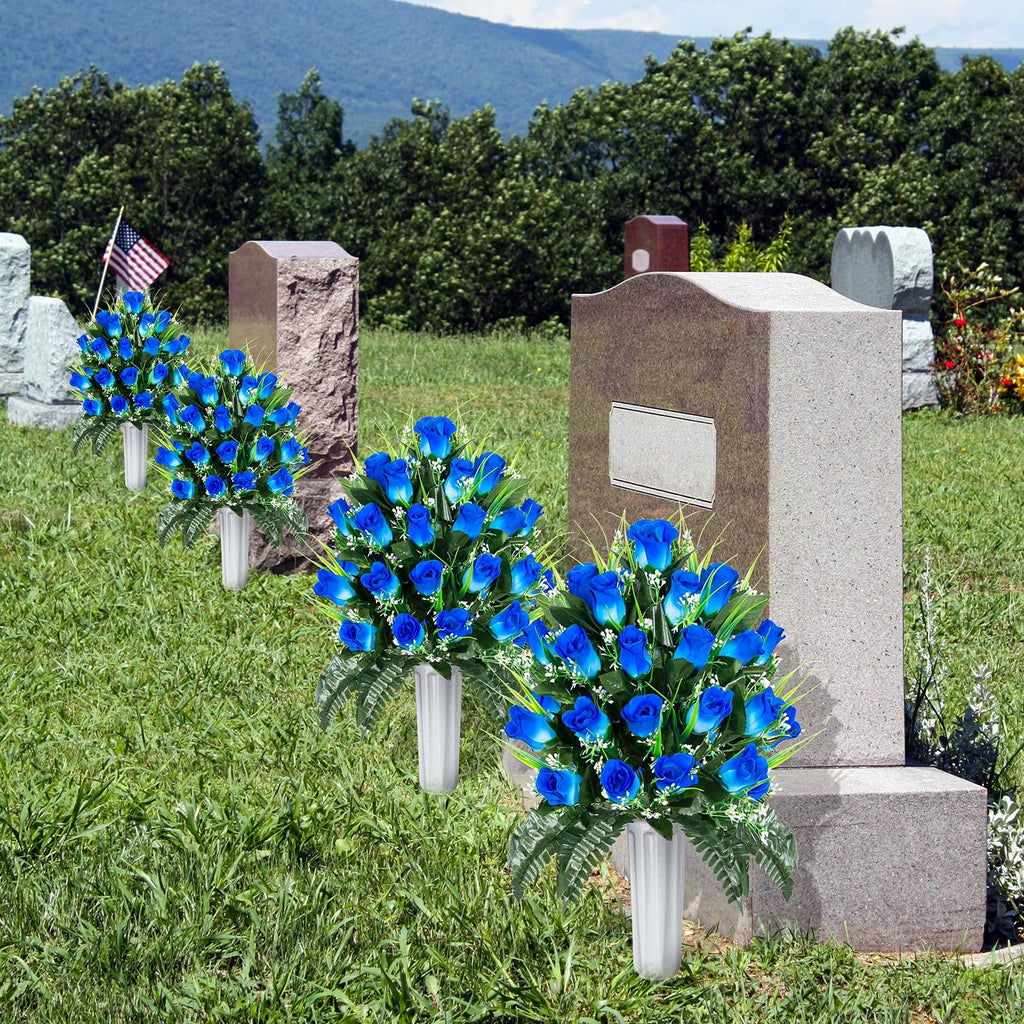 Two sets of artificial blue rose bouquets in white vases placed at cemetery headstones with an American flag.