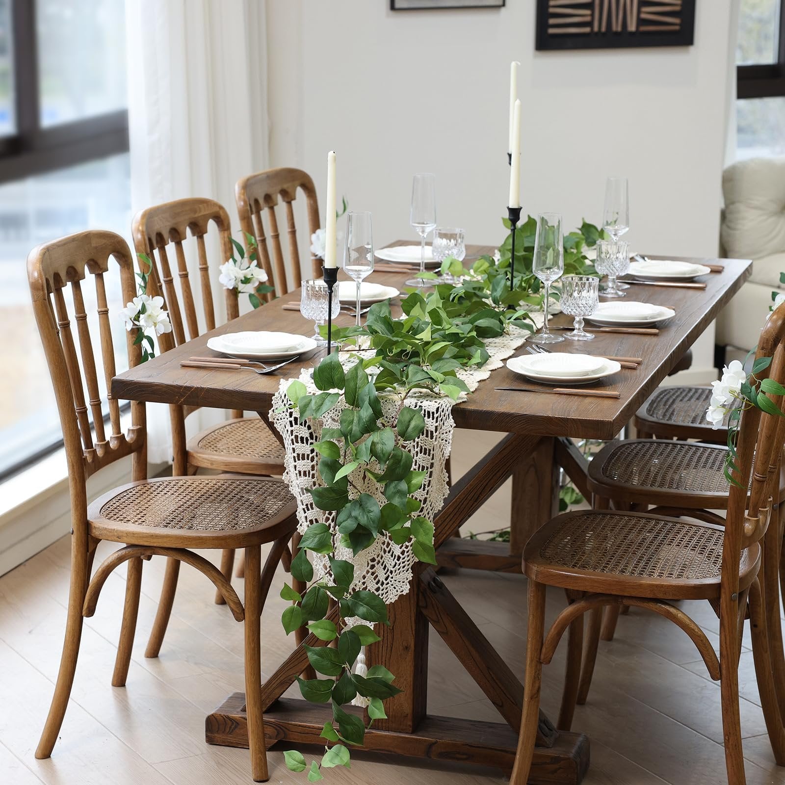 Dining table set with artificial green vine garland and white flowers on chairs