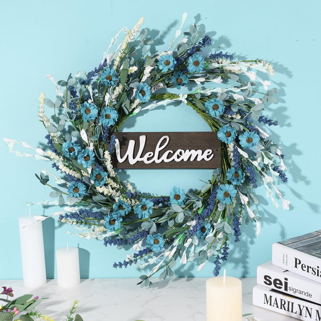 Artificial blue forsythia wreath with a wooden welcome sign, displayed against a light blue wall.
