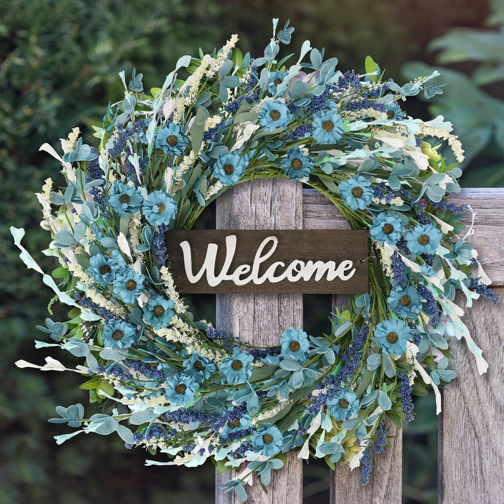 Artificial blue forsythia wreath with a welcome sign hanging on a wooden fence