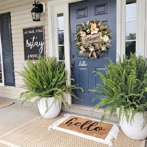 Magnolia wreath with buffalo plaid bow and BLESSED wooden plaque on a navy blue front door.
