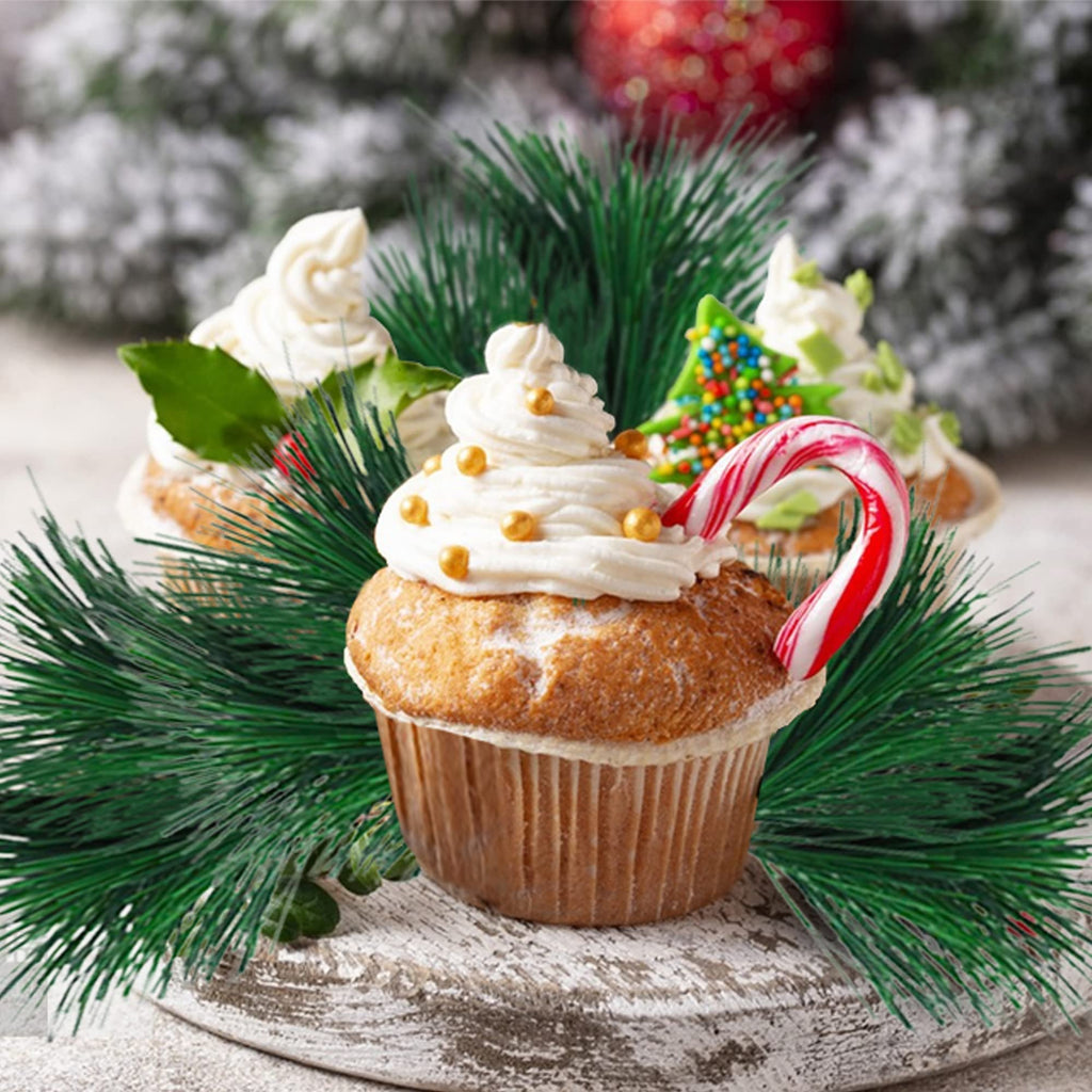 Festive cupcakes decorated with white frosting, gold sprinkles, and candy canes, surrounded by artificial pine branches and a blurred snowy background.