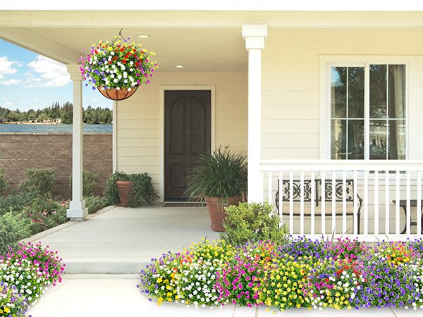 Artificial flowers in red, purple, white, and yellow displayed in a hanging basket and along a porch walkway.