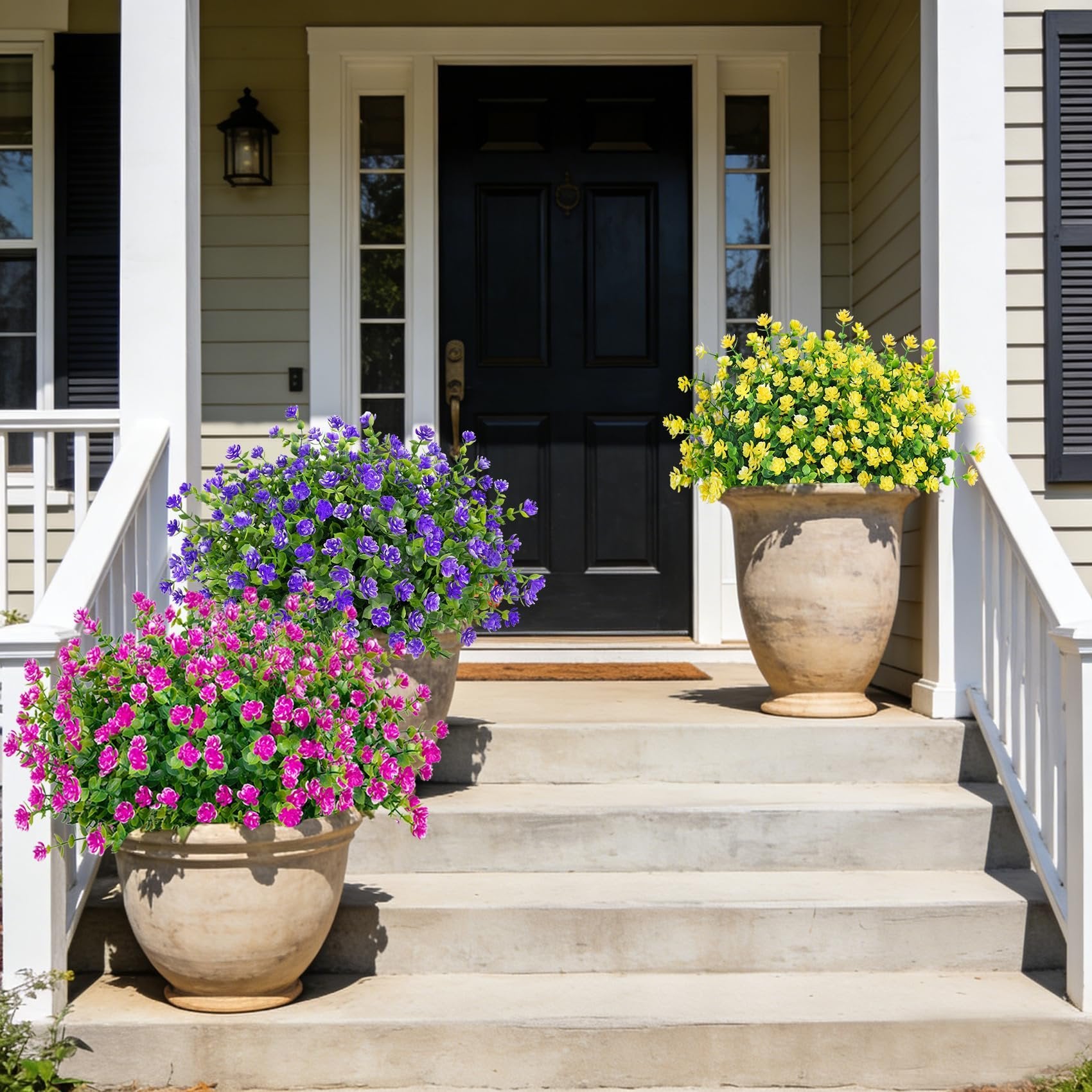Three large planters with colorful artificial flowers decorating a front porch staircase.