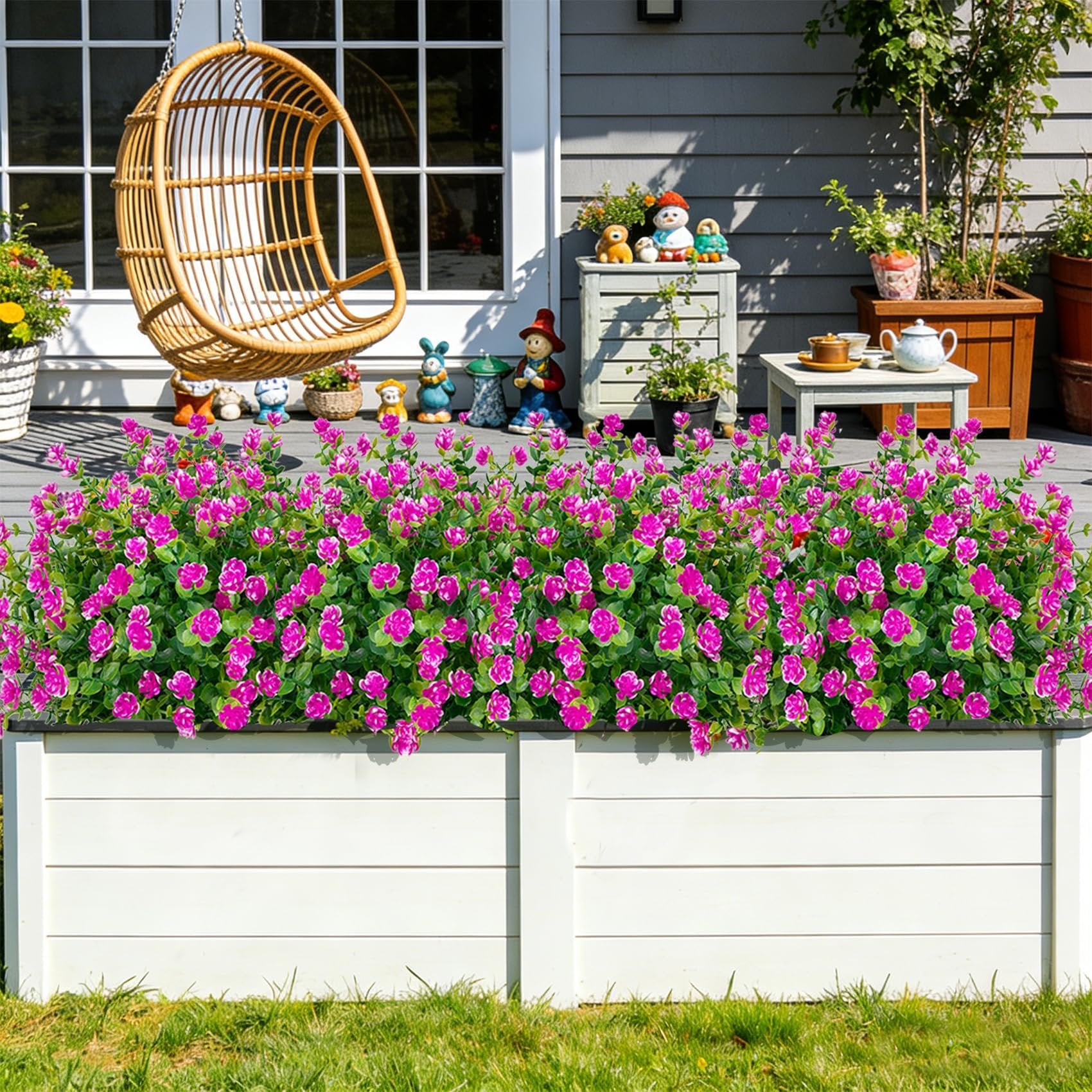 Artificial pink flowers in a white planter on a deck with a hanging chair and garden decor
