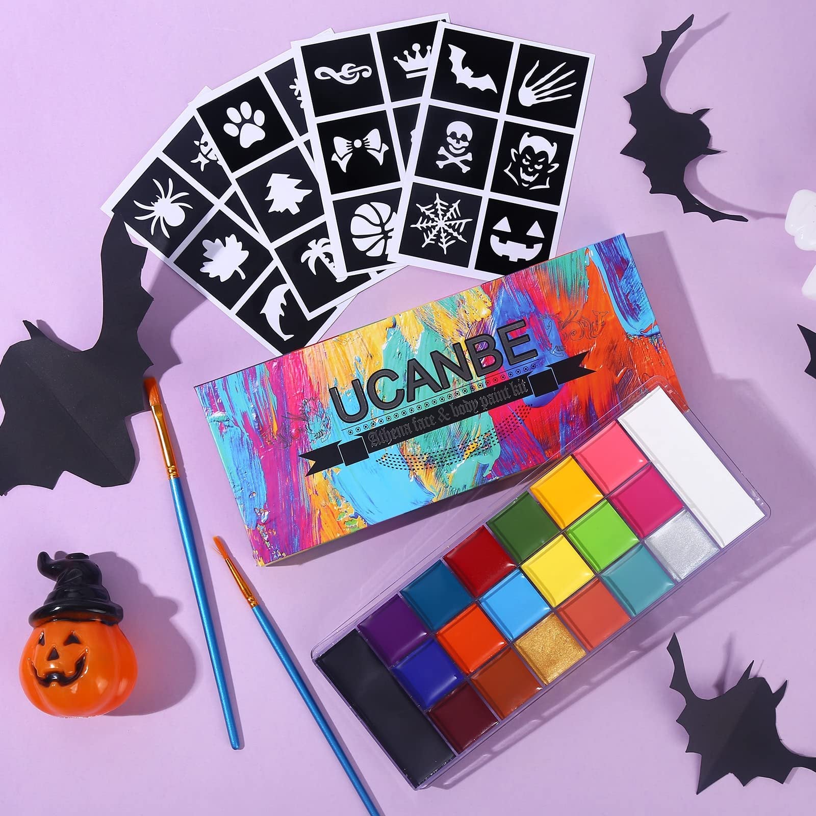 20-color face and body paint kit with stencils and brushes, arranged on a purple background with Halloween decorations.
