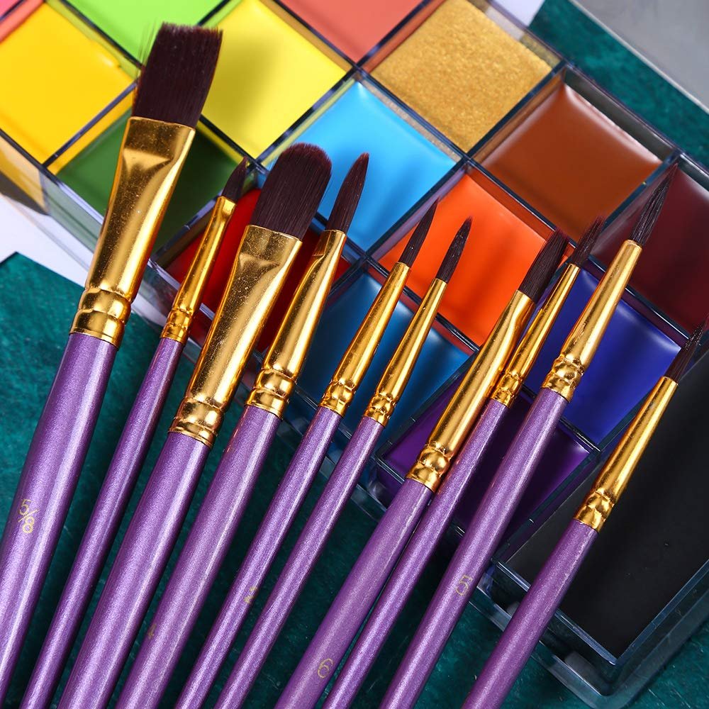 Close-up of purple paintbrushes fanned out in front of a palette of colorful oil-based face and body paints.