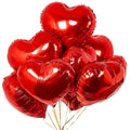 A cluster of shiny red heart-shaped foil balloons with gold ribbons against a white background.
