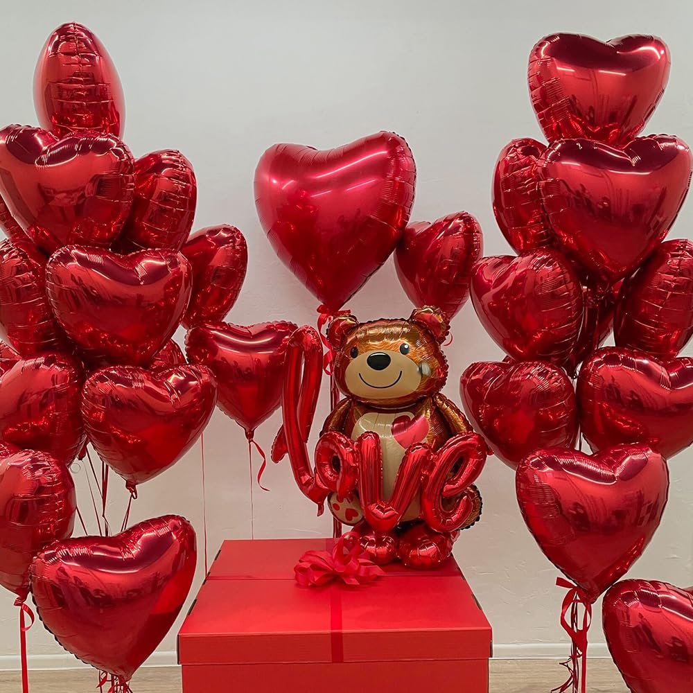 Red heart and teddy bear foil balloons with 'LOVE' text, arranged around a red gift box.