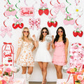 Three women in party dresses holding disco balls, with strawberry-themed hanging decorations and flowers in the foreground.
