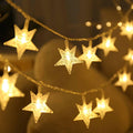 Warm white star-shaped string lights with LED bulbs, close-up view showing multiple illuminated stars on a wire.
