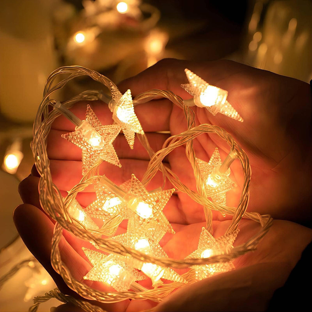 Hands holding warm white star-shaped LED string lights, illuminated.