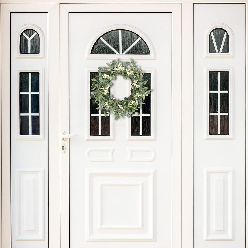 Eucalyptus wreath with white berries hanging on a white double door